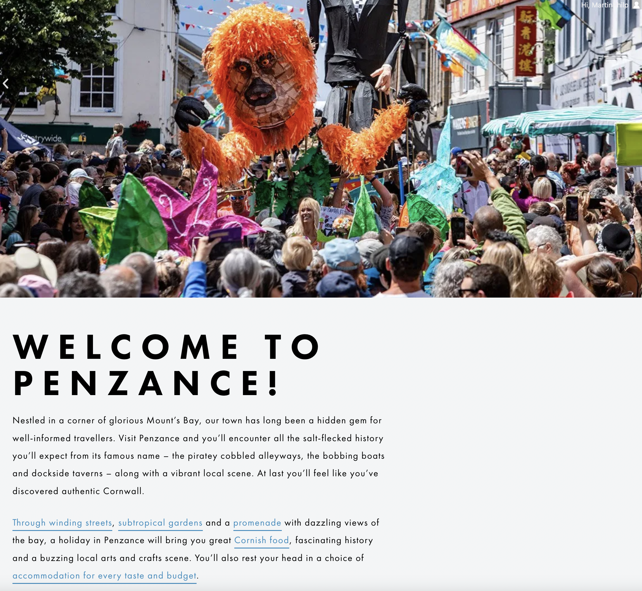 Screengrab of the Love Penzance homepage with a crowd looking at a giant orange puppet: Penzance BID is a long-term content marketing client of our Penzance-based Cornish marketing agency.